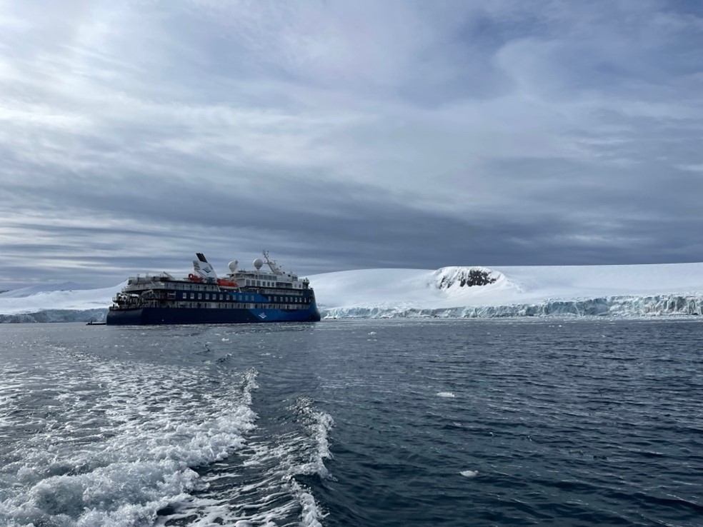 A cruise ship in front of a glacier